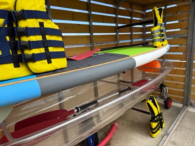 Water sports equipment storage with colorful SUP boards, kayaks, and life jackets
